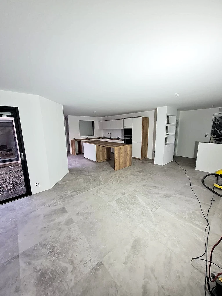 Sol en grand format effet marbre dans une pièce de vie ouverte sur la cuisine